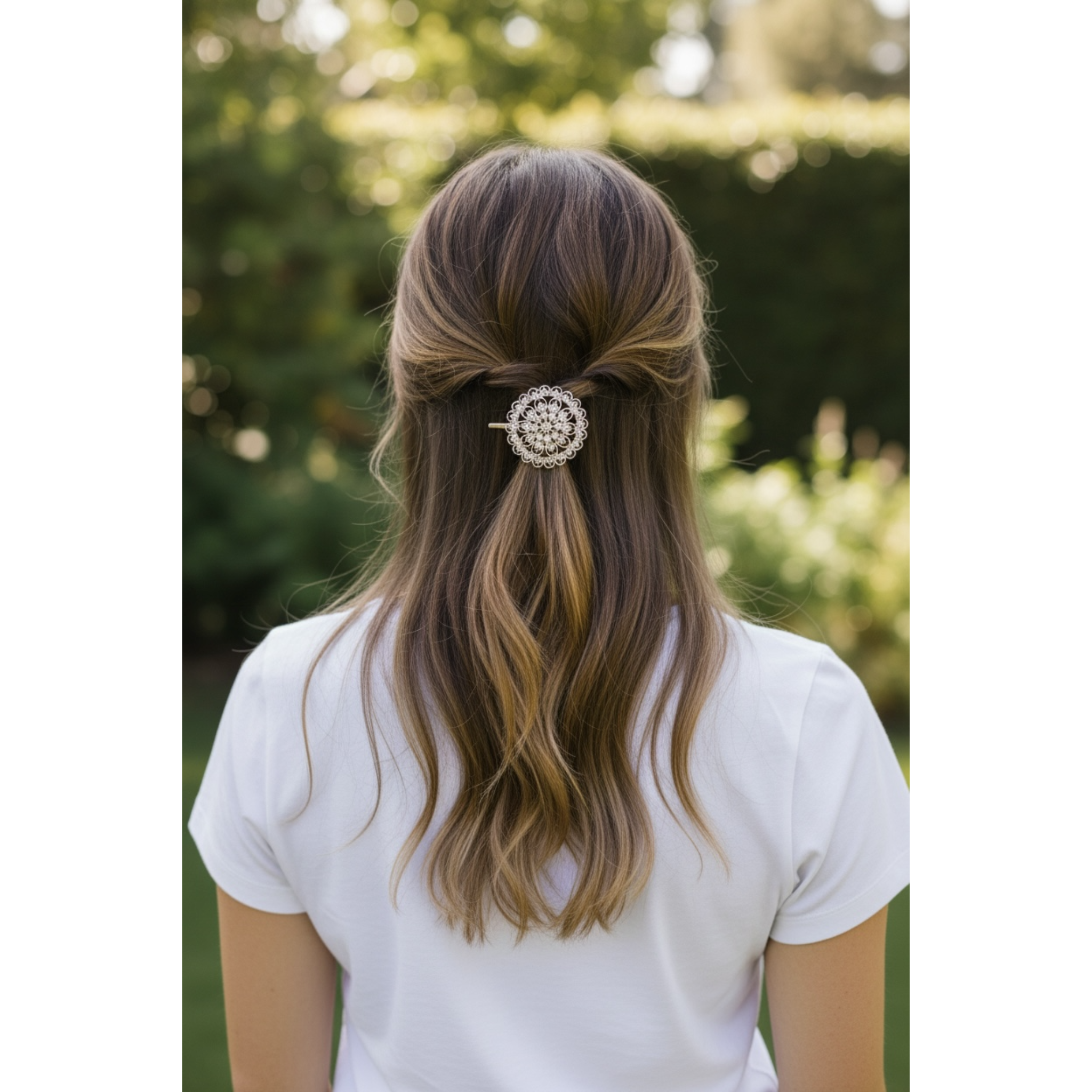Person with a decorative hairclip in their hair, standing outdoors with greenery in the background