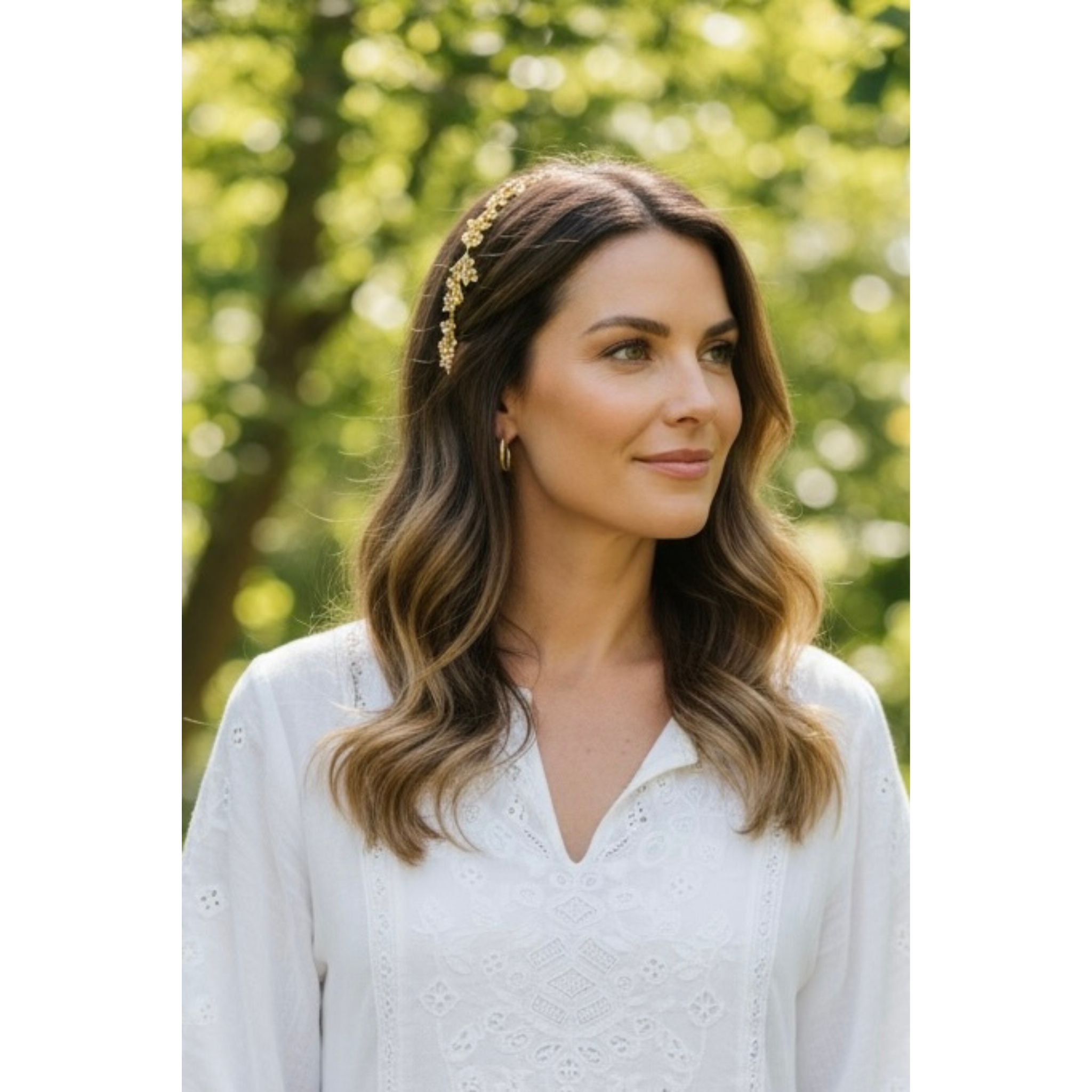 Woman wearing a gold headband outdoors with greenery in the background