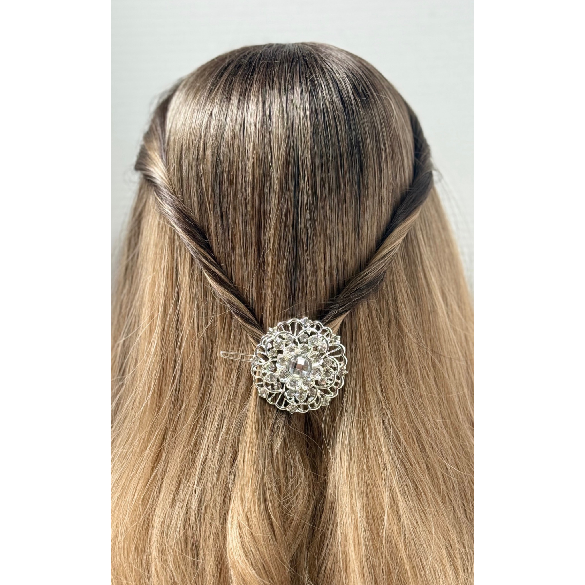 Hair accessory with a decorative brooch in a person's hair on a plain background