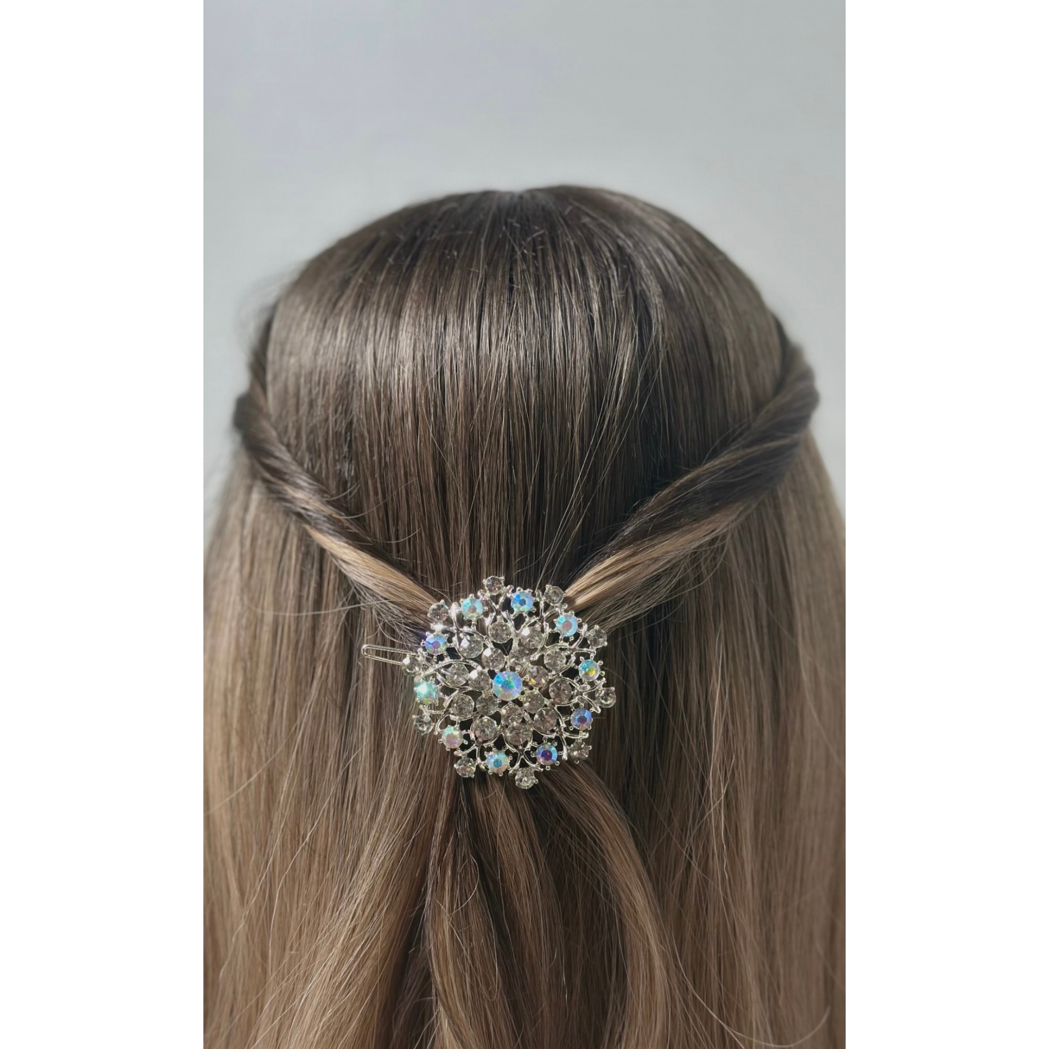 Hair bun with a decorative hair clip featuring crystals on a plain background