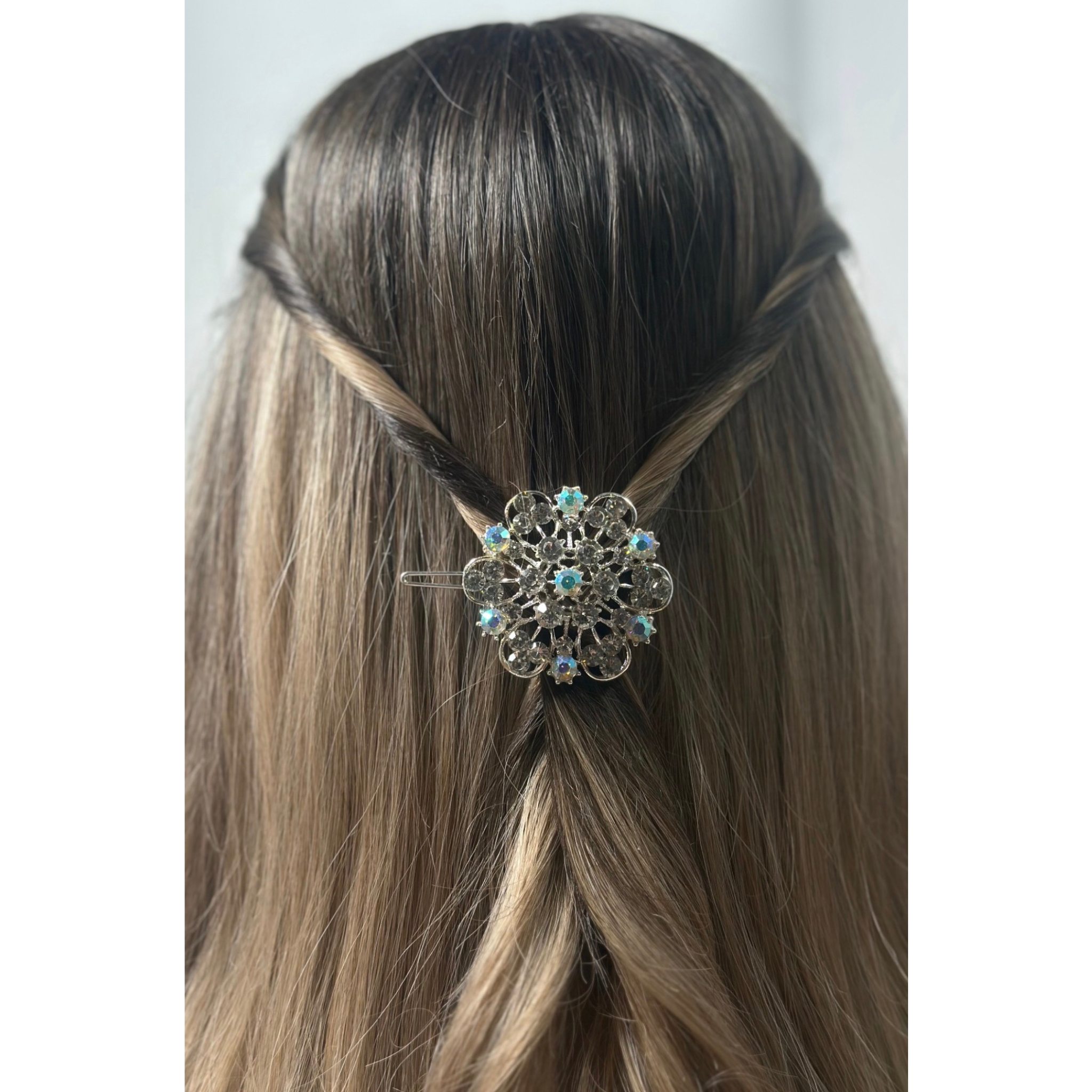 Decorative hair clip in a person's braided hair against a neutral background