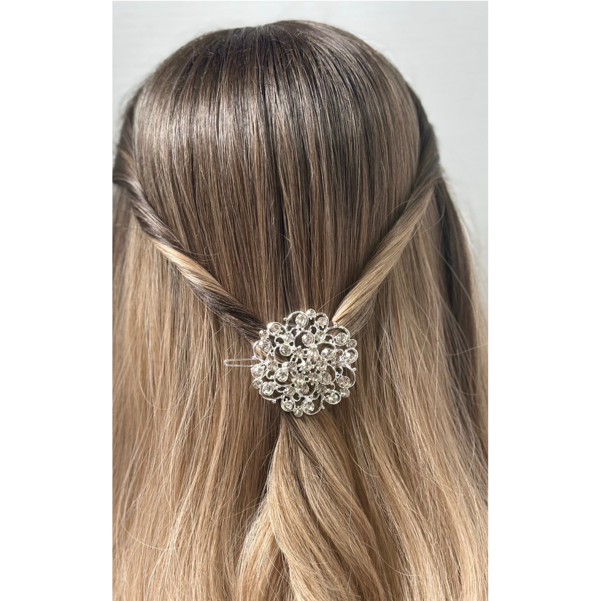 Hair clip with decorative design in a person's hair on a plain background