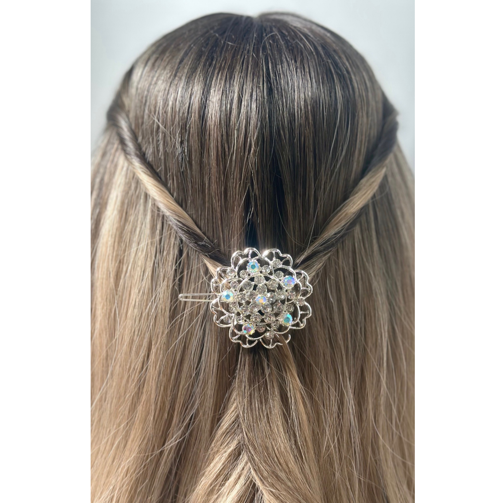 Silver hair clip with gemstones on a person's head against a white background