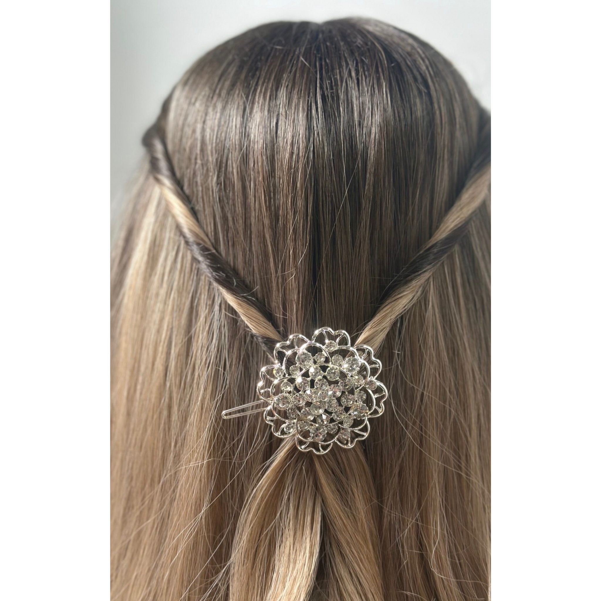 Hair accessory with decorative element in a braided hairstyle on a plain background