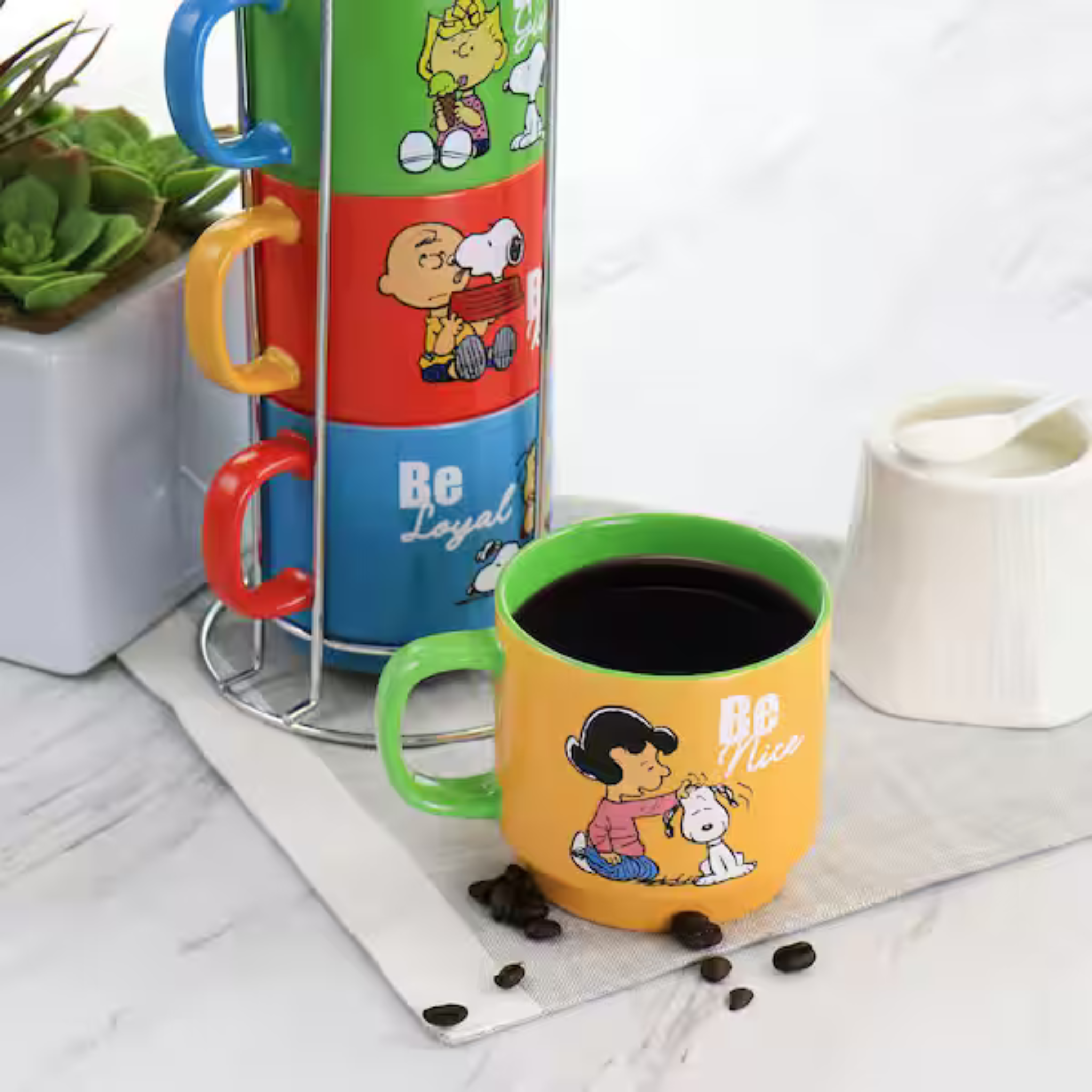 Colorful mugs with cartoon characters and text on a marble surface.