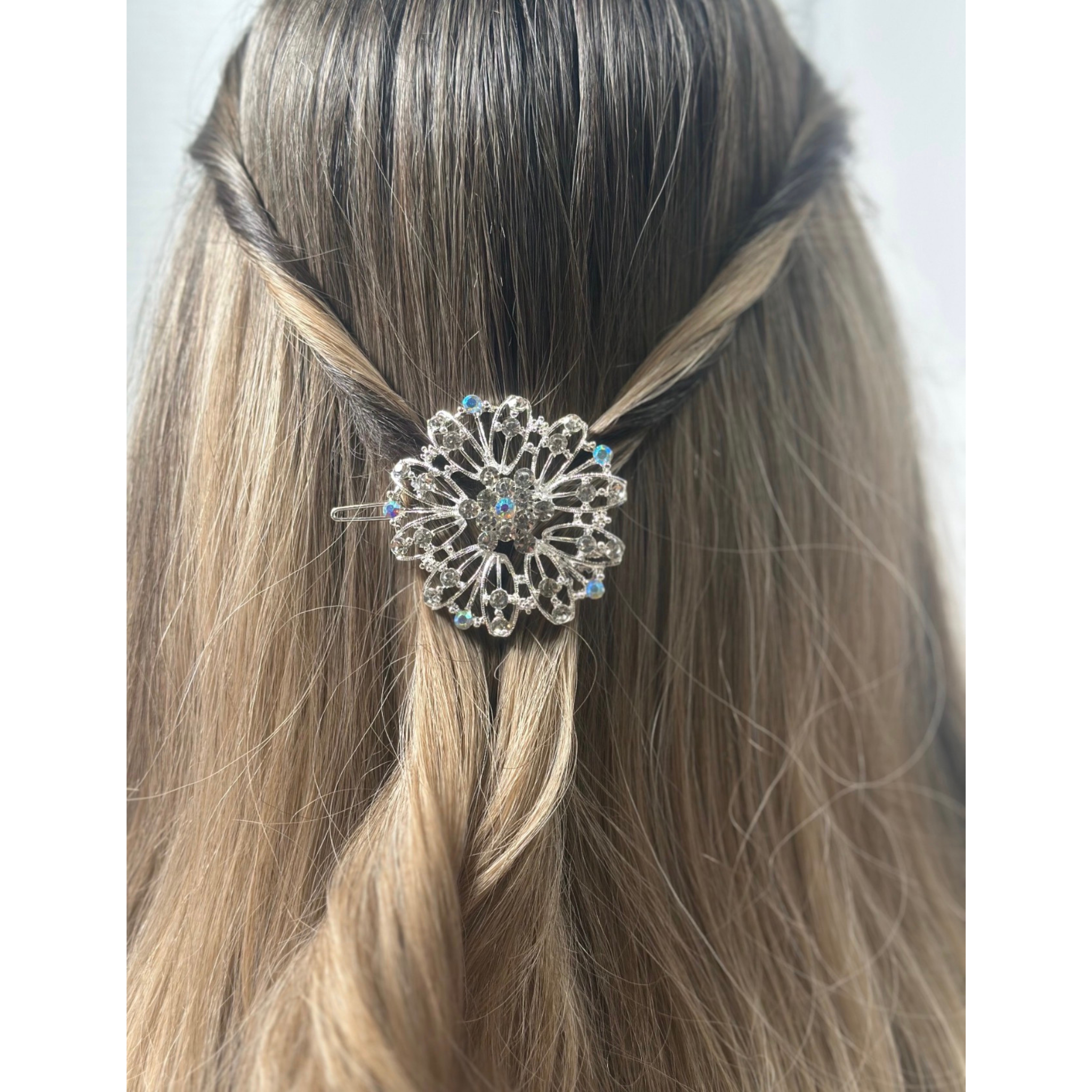 Decorative hair clip in a person's braided hair against a white background