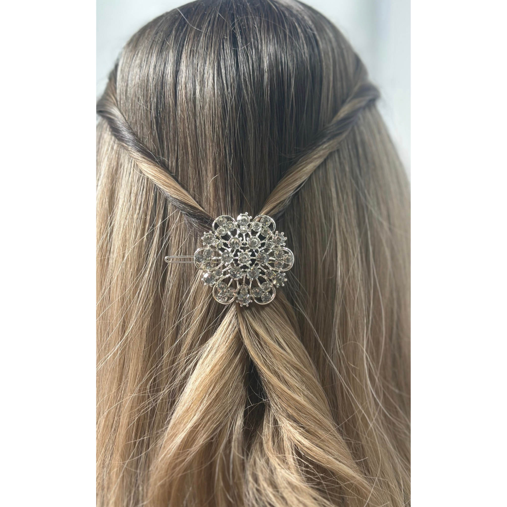 Silver hair clip with decorative design in a person's hair on a white background