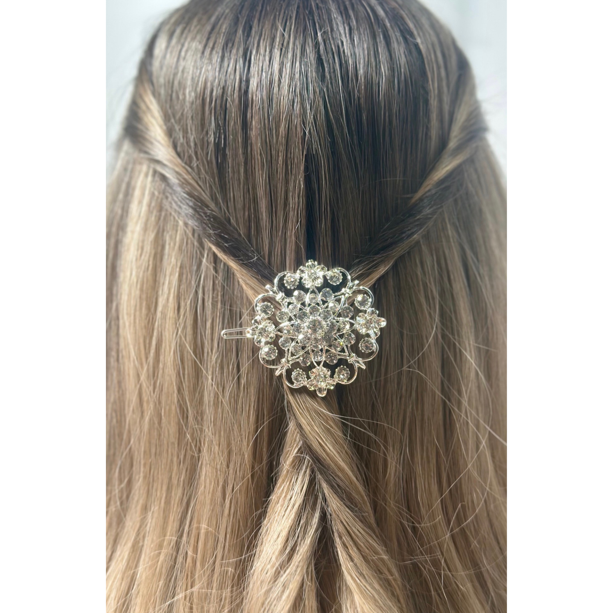 Hair accessory with crystals in a braided hairstyle on a plain background
