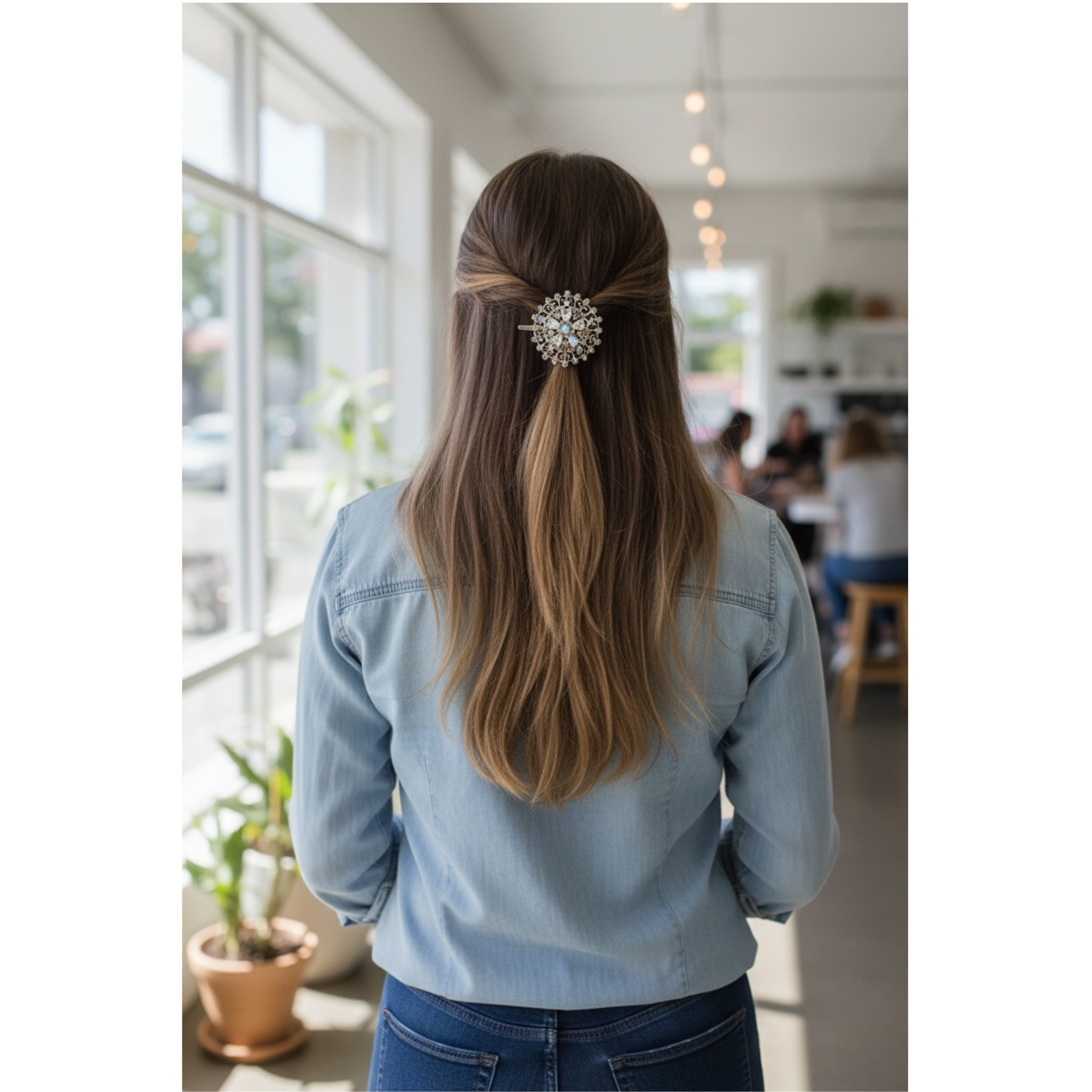 Person with long hair tied back with a decorative hairpin, wearing a denim jacket, in a room with large windows.