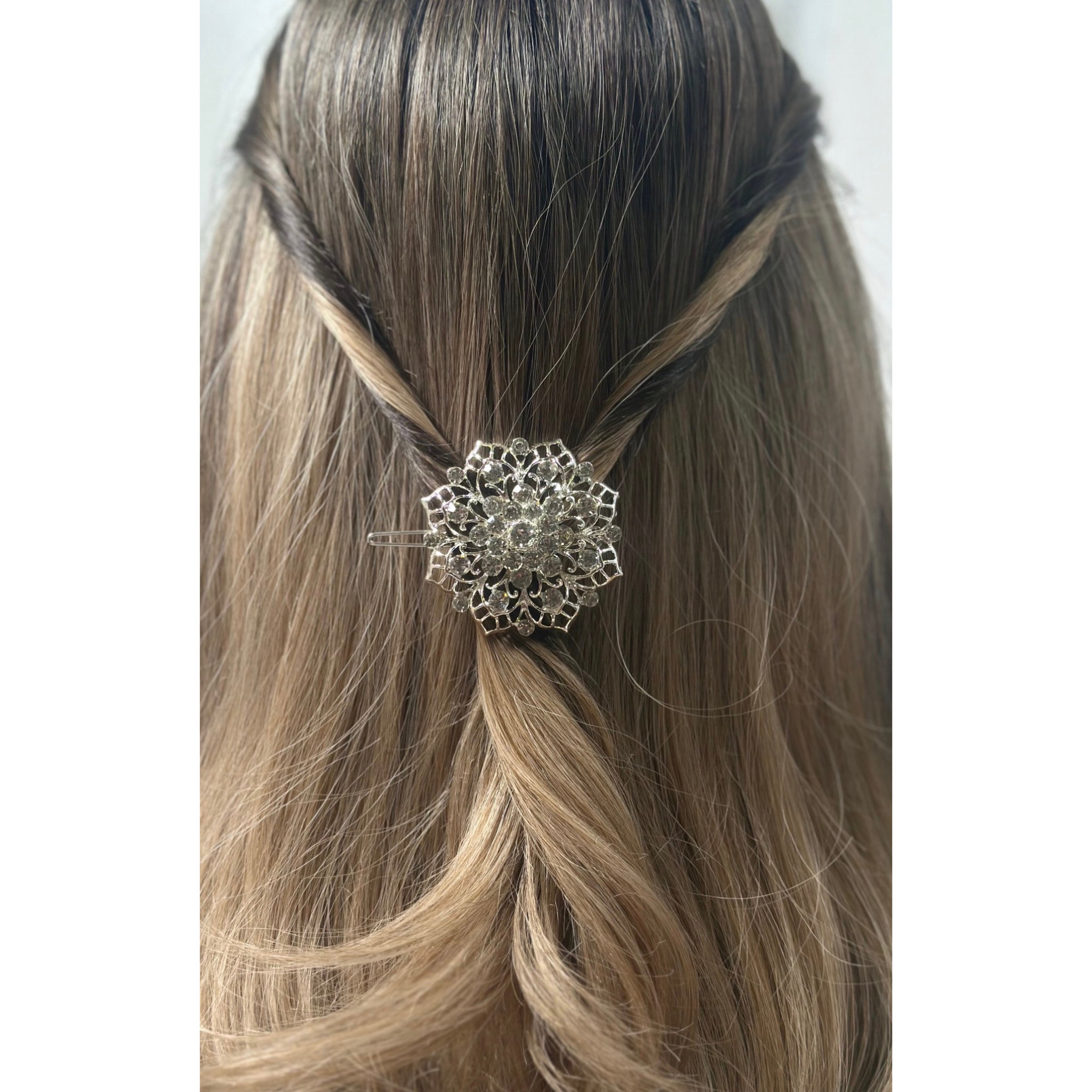 Silver hair clip on a person's hair with a plain background