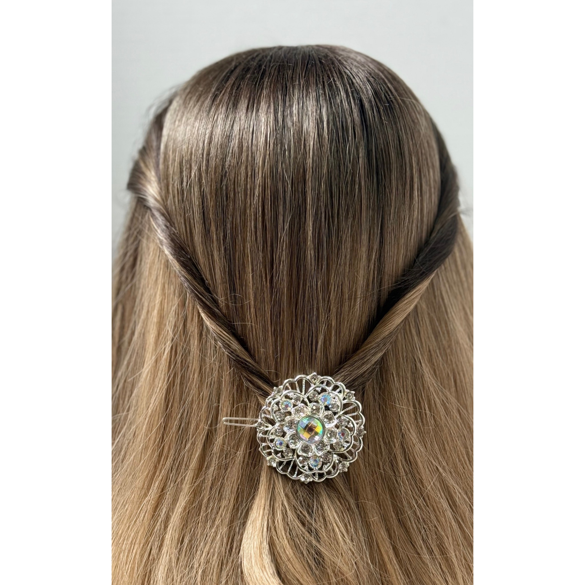 Hair accessory with a decorative brooch in a person's hair on a plain background