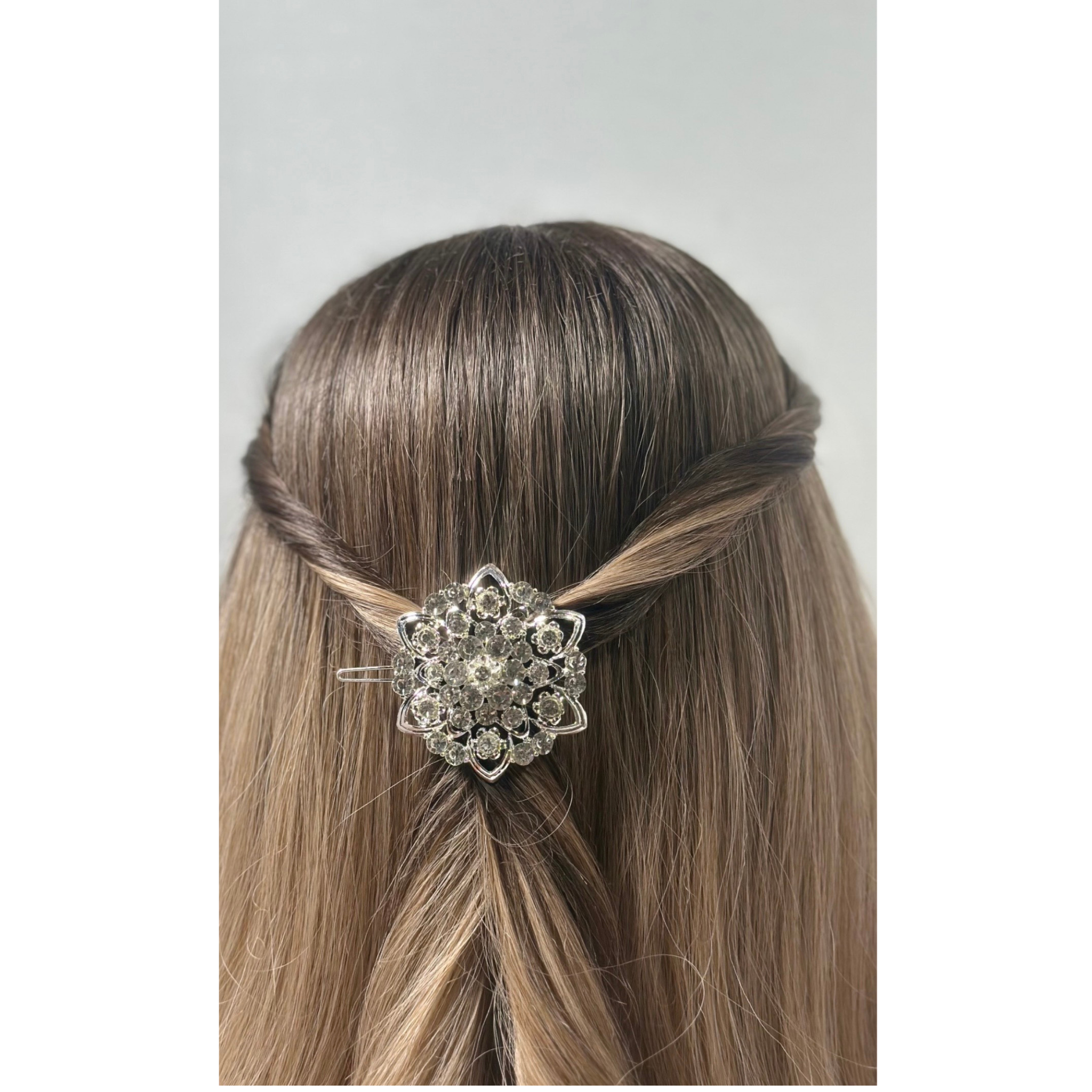Hair clip with decorative element in a styled hair arrangement on a plain background