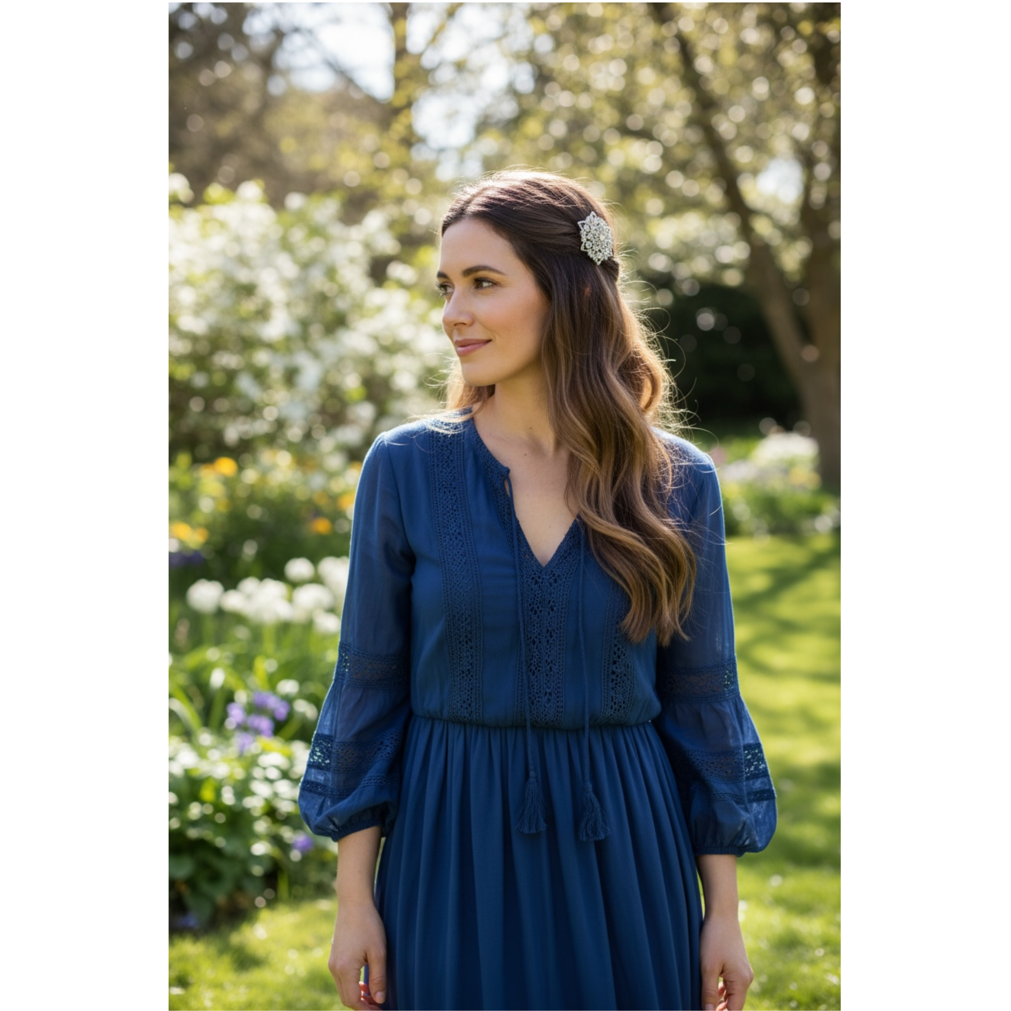 Woman in a blue dress standing in a garden with greenery and flowers in the background. This image showcases the hair clip on the woman's hair. 