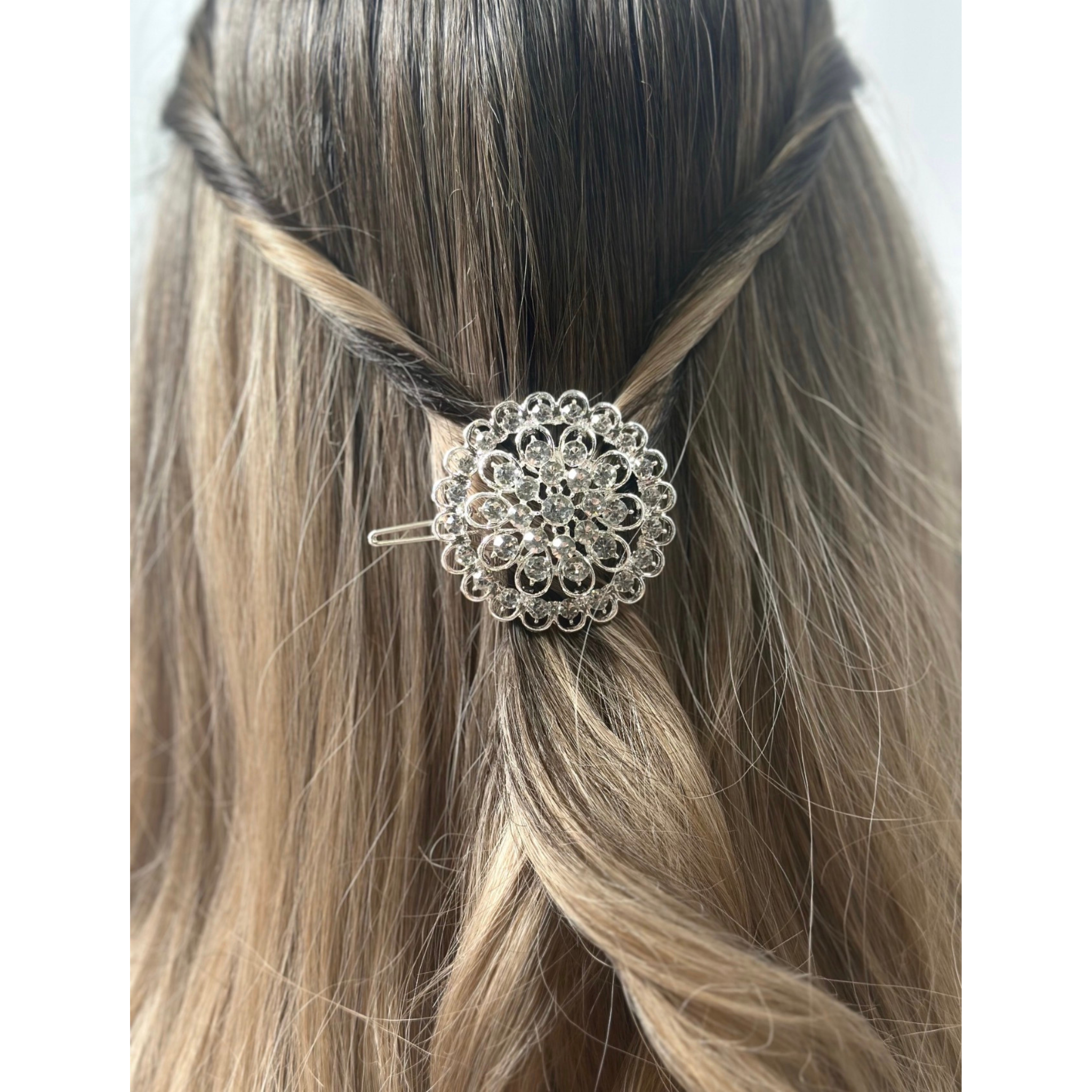 Silver decorative hair clip in a person's braided hair on a white background