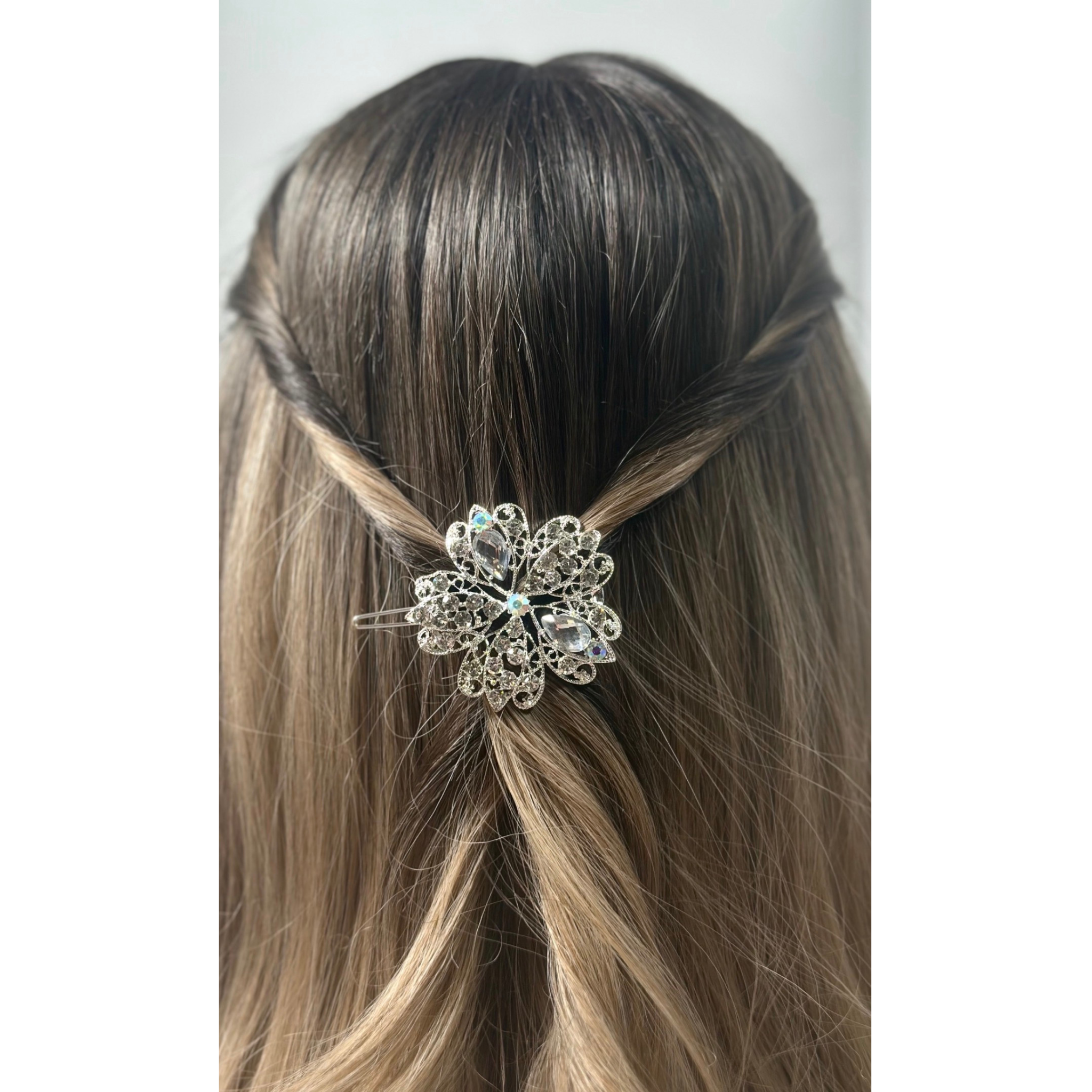 Hair accessory with a decorative multicolor flower clip on a woman's hair against a neutral background