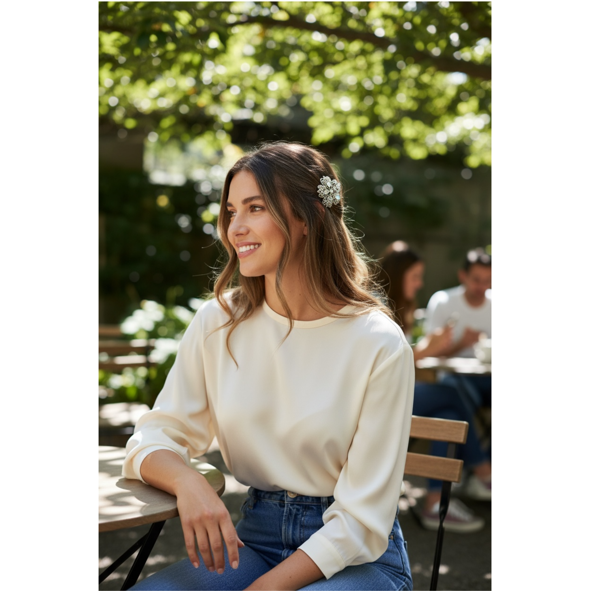 Woman sitting outdoors in a garden setting, wearing a white sweater and blue jeans. This image is showcasing the beautiful decorative hair clip she is wearing in her nicely styled hair.