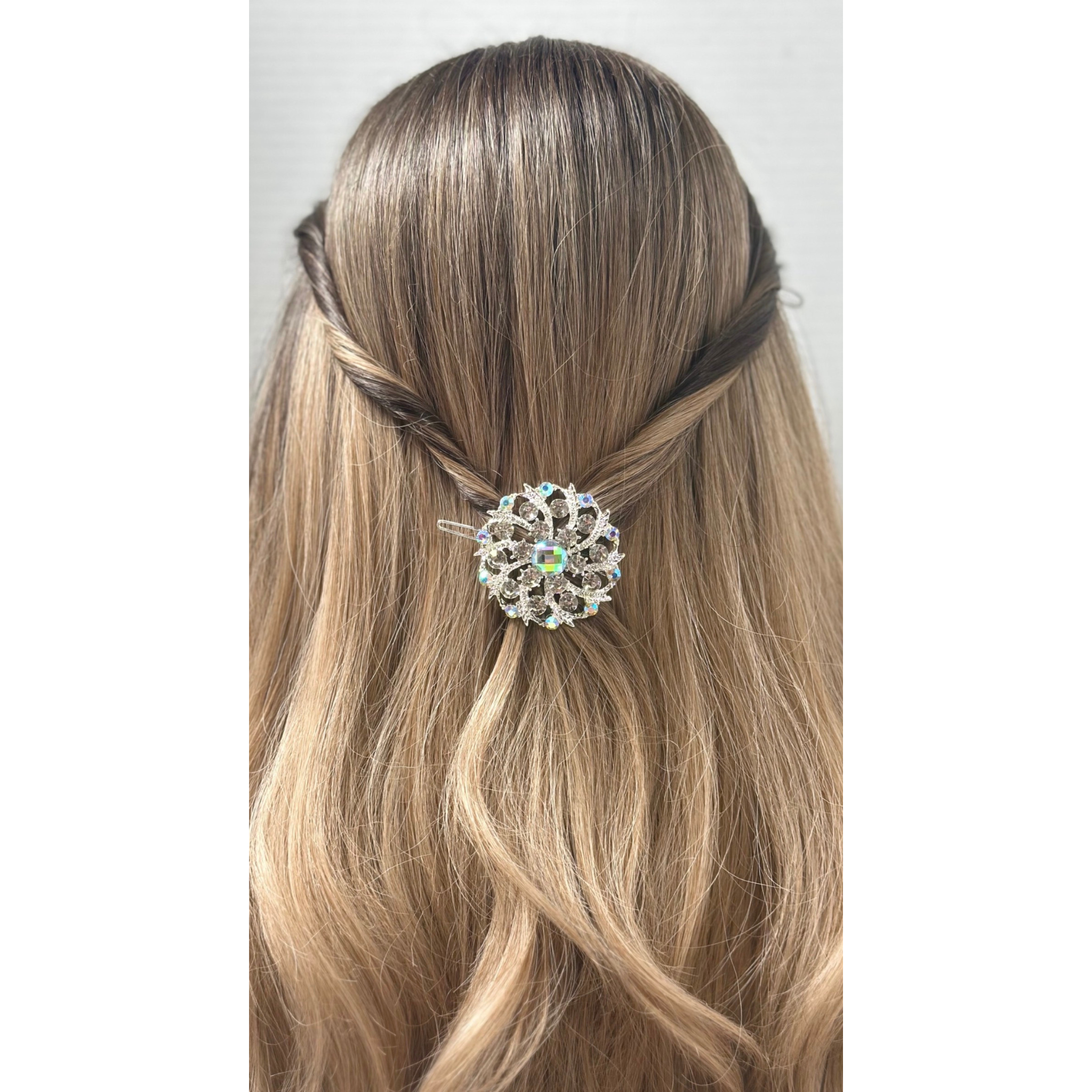 Hair accessory with a decorative brooch on a person's hair against a white background