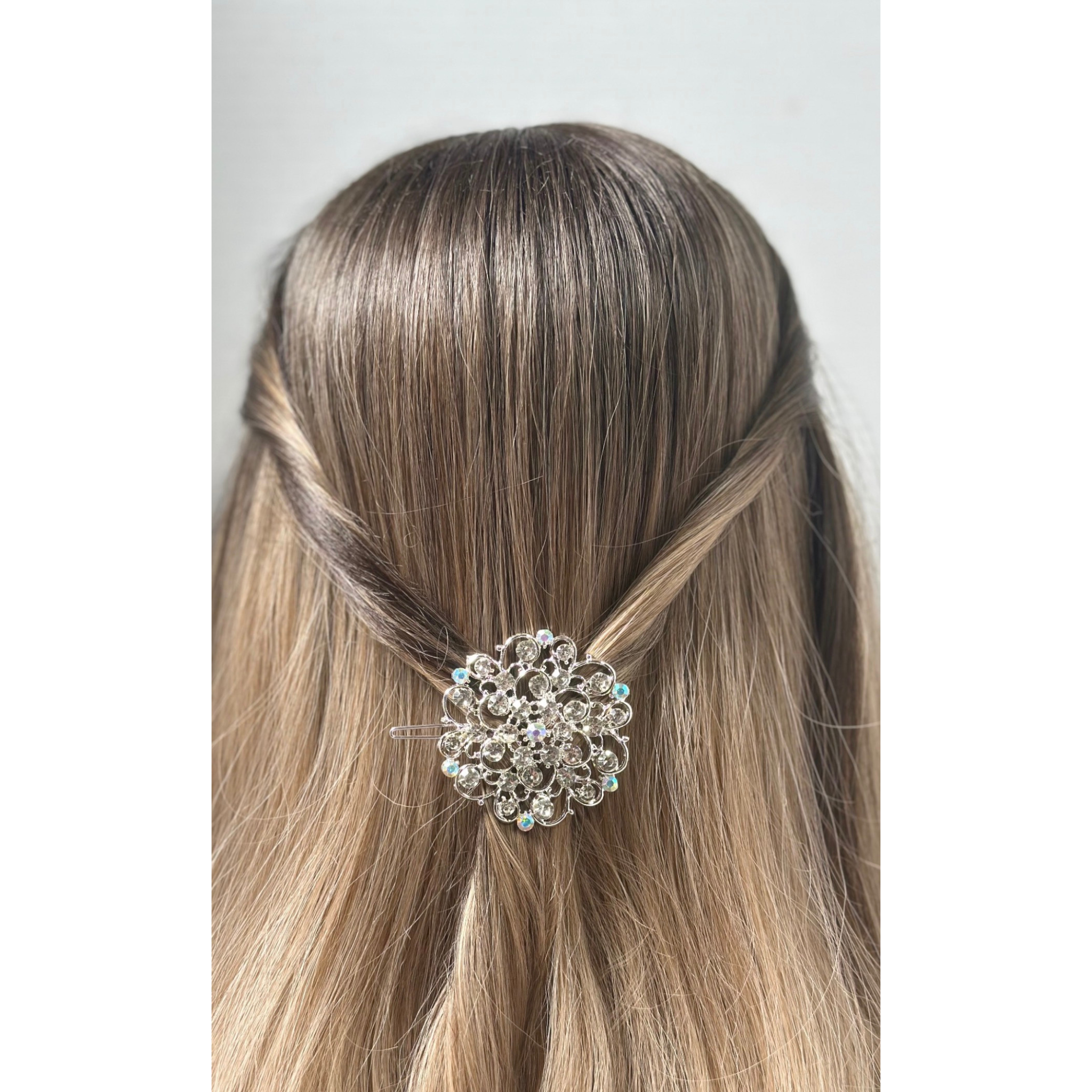 Hair accessory with a decorative brooch in a person's hair on a plain background