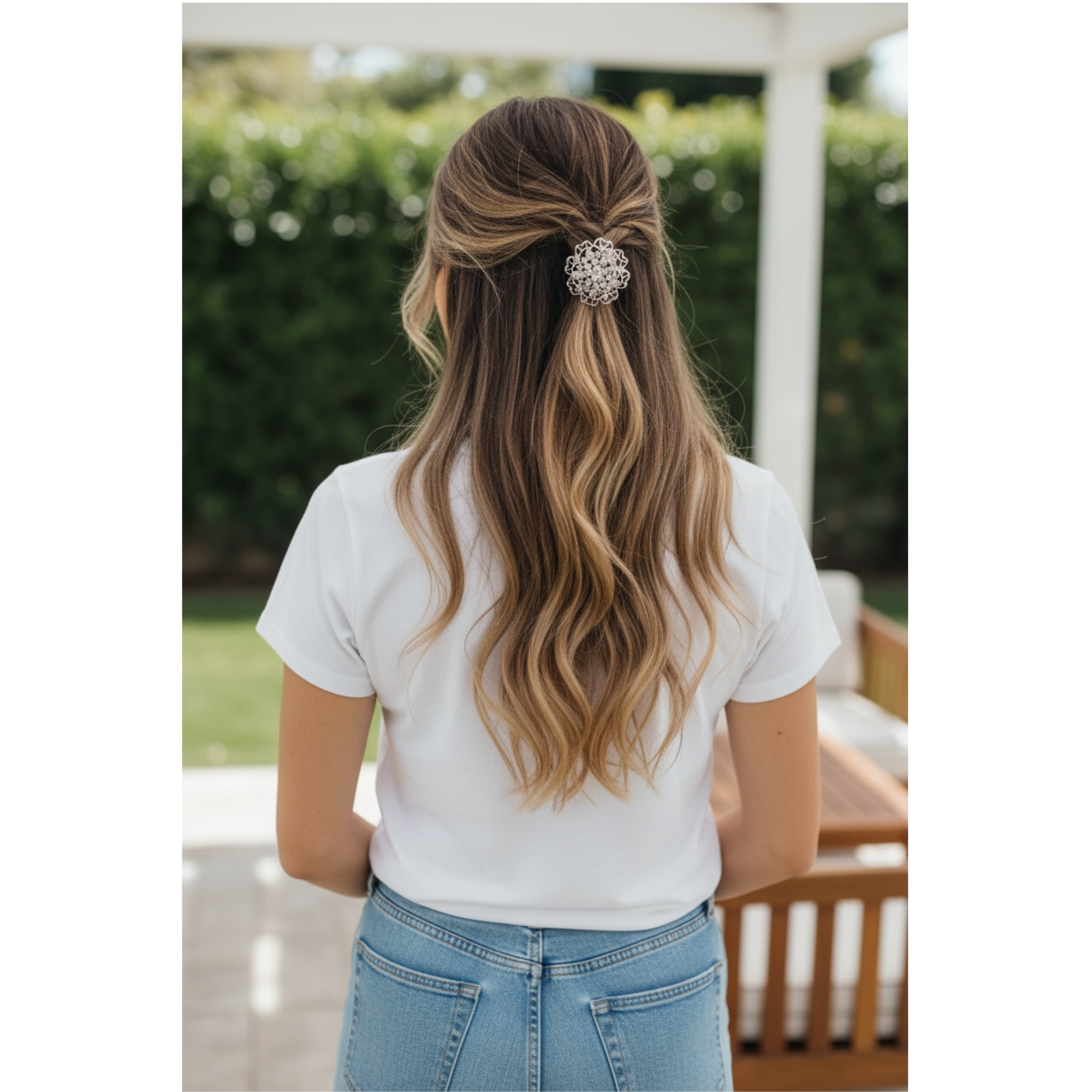 Person with long, wavy hair wearing a white shirt and blue jeans outdoors.