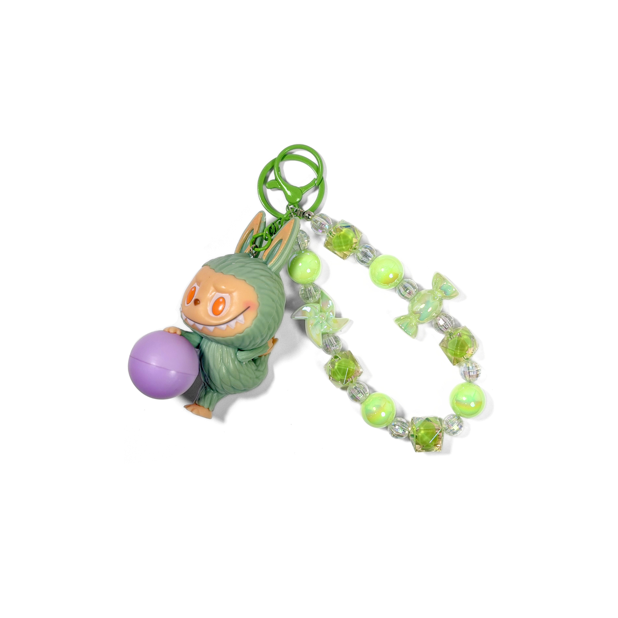 Labubu Lazy Yoga Keychain, labubu holding a purple ball and on a beaded green keychain on a white background